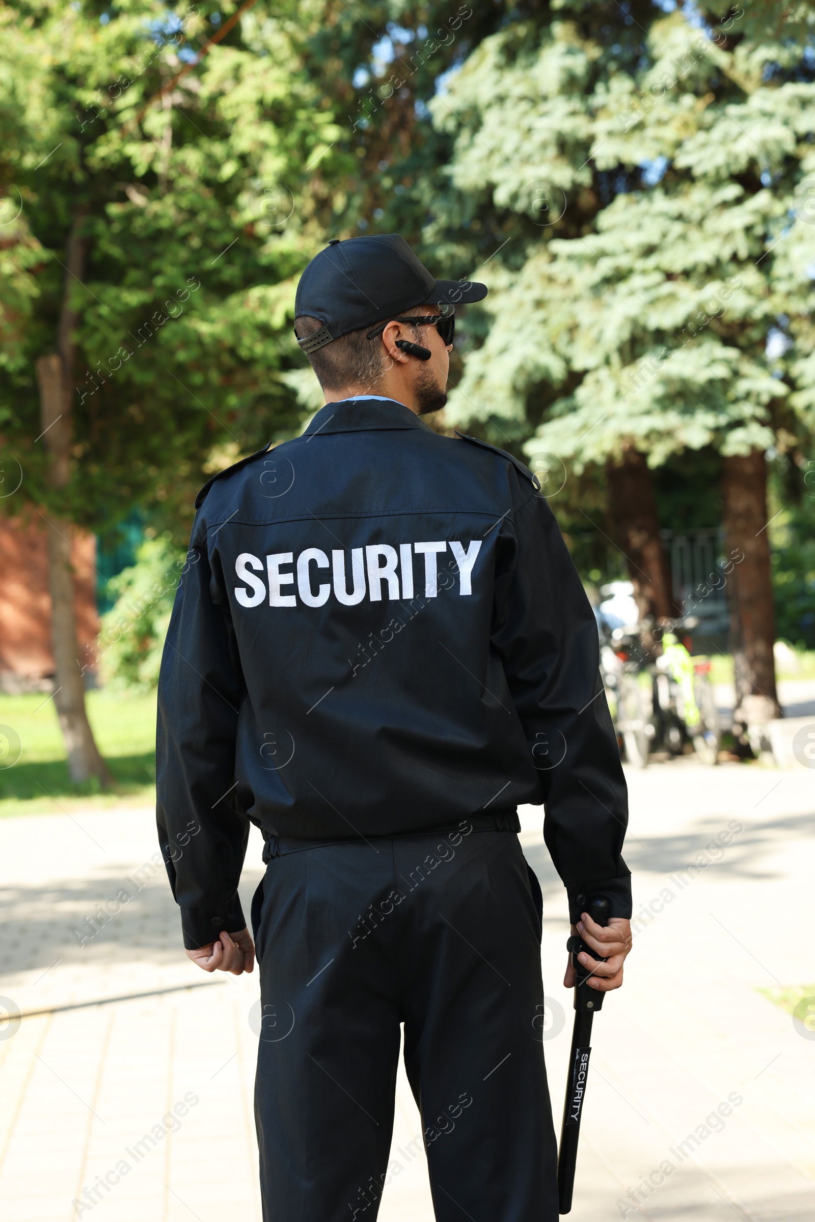 Photo of Security guard in uniform with baton outdoors, back view