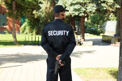 Security guard in uniform with gun outdoors, back view