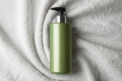 Photo of Bottle of shampoo on soft terry towel, top view