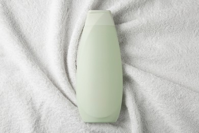 Photo of Bottle of shampoo on soft terry towel, top view