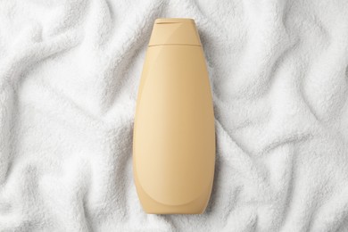 Photo of Bottle of shampoo on soft terry towel, top view