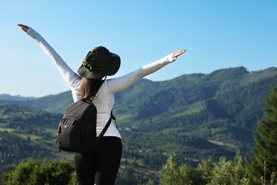 Woman with backpack in beautiful mountains, back view. Space for text