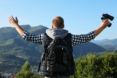 Photo of Man with backpack and binoculars in beautiful mountains, back view