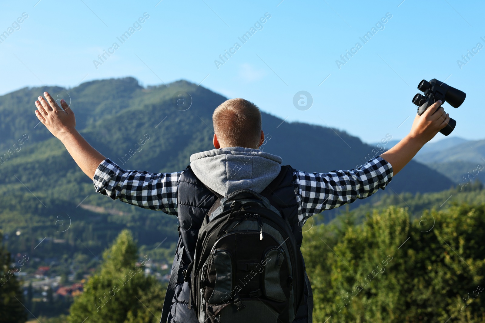 Photo of Man with backpack and binoculars in beautiful mountains, back view