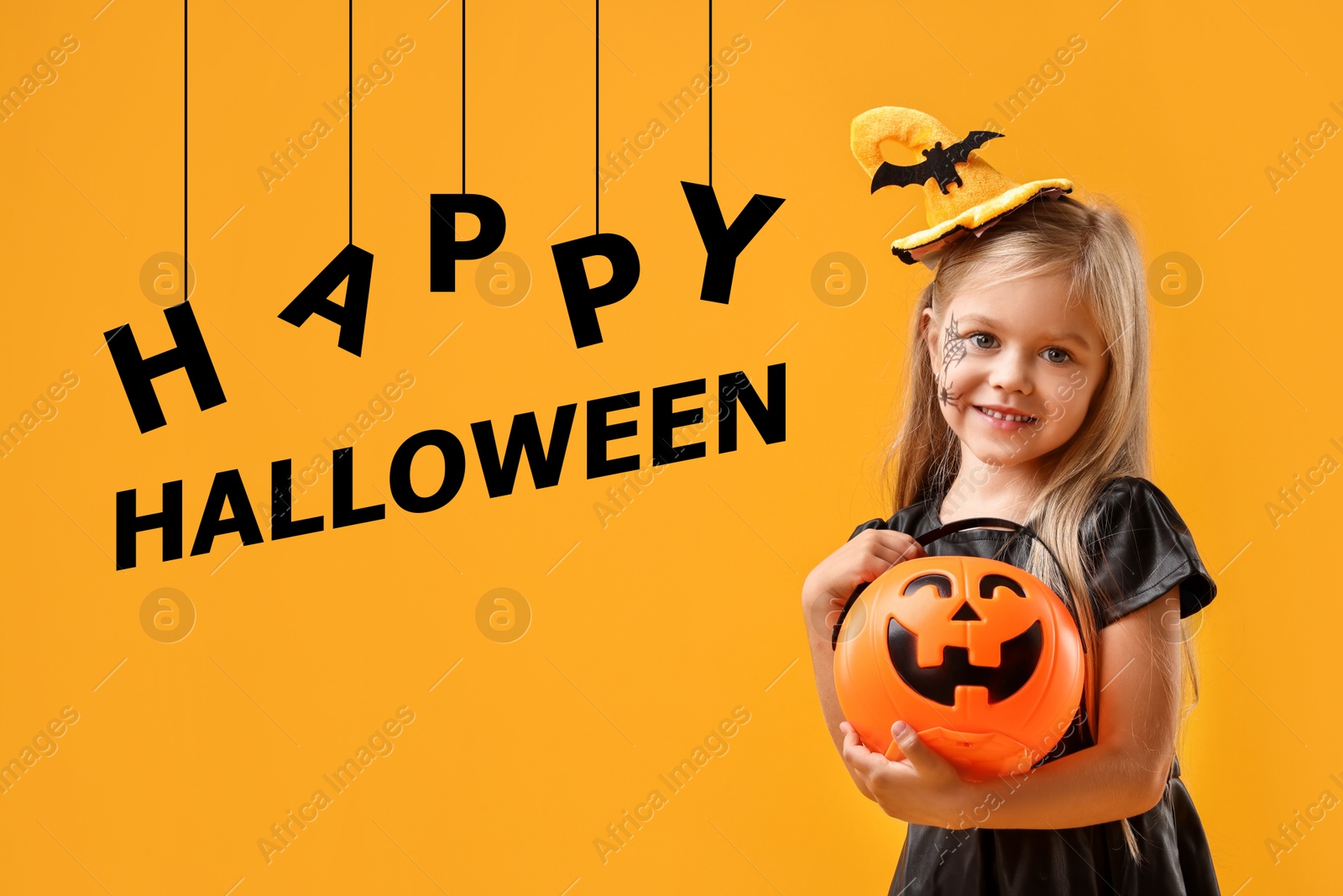 Image of Happy Halloween card. Girl dressed like witch holding pumpkin bucket on orange background