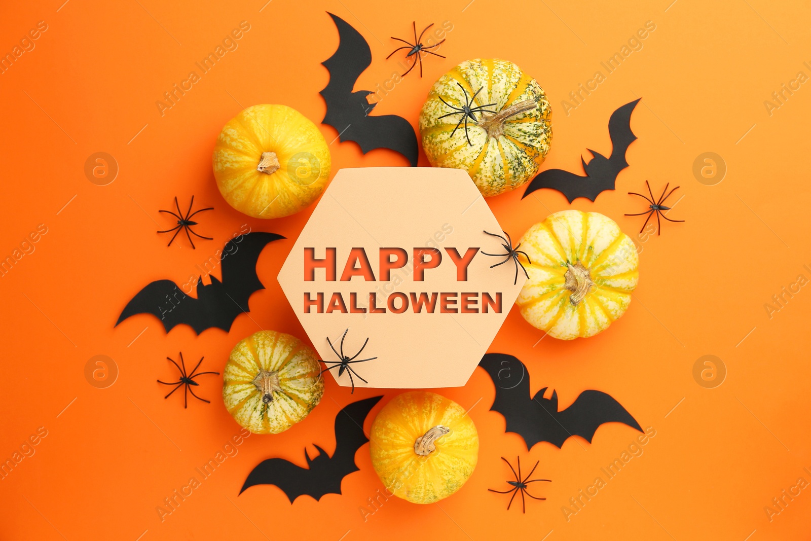 Image of Happy Halloween text, pumpkins and bats on orange background, top view. Greeting card