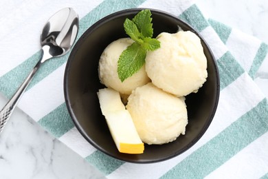 Scoops of tasty melon sorbet with mint in bowl and spoon on white table, flat lay