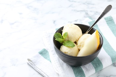 Photo of Scoops of tasty melon sorbet with mint and spoon in on white marble table, space for text