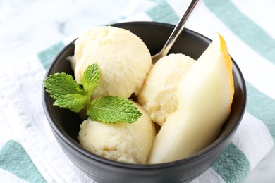 Photo of Scoops of tasty melon sorbet with mint and spoon in on white table, closeup