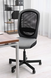 Photo of Black chair and wooden desk in office