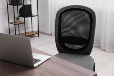 Photo of Black chair, laptop and desk in office