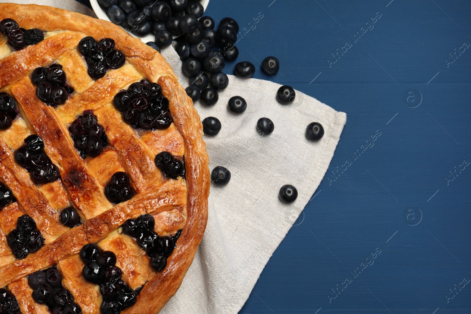 Photo of Tasty homemade pie with blueberries on blue wooden table, flat lay. Space for text