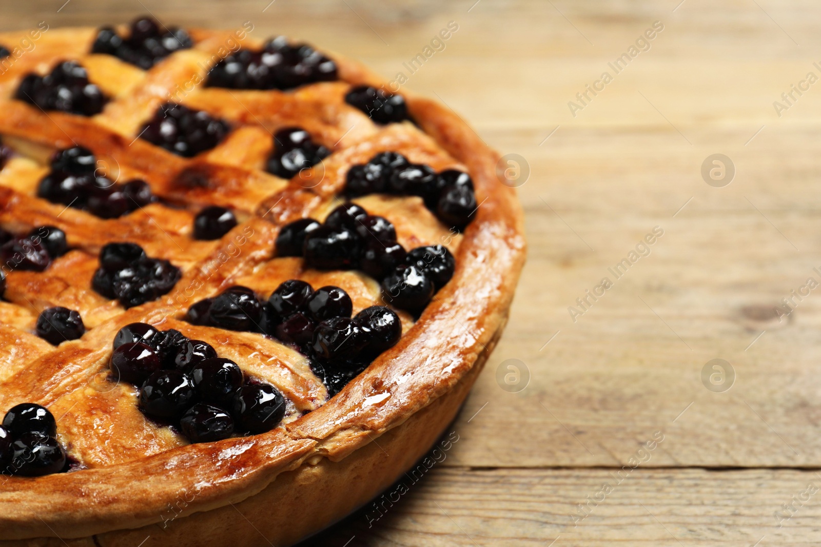 Photo of Tasty homemade pie with blueberries on wooden table, closeup. Space for text