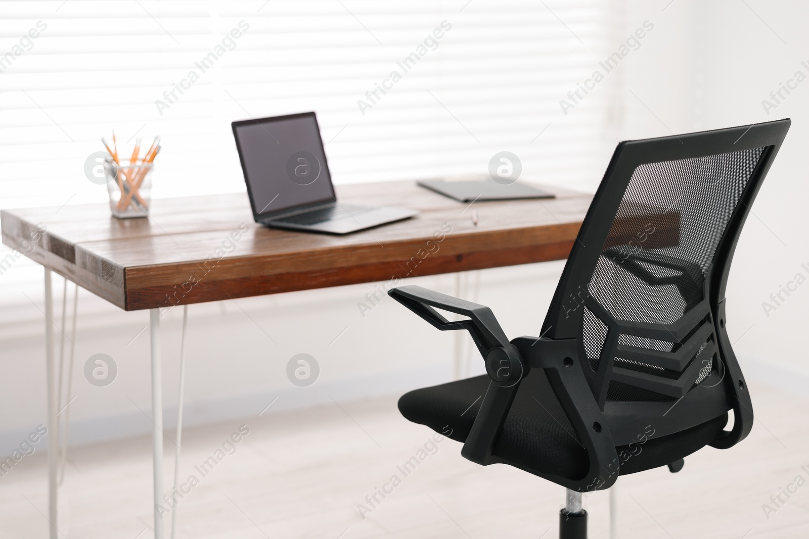 Photo of Black chair, laptop and desk in office