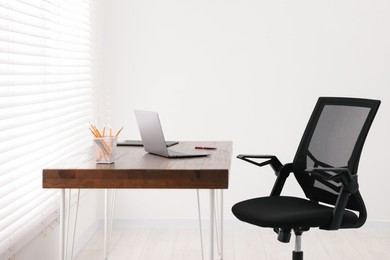 Black chair, laptop and desk in office