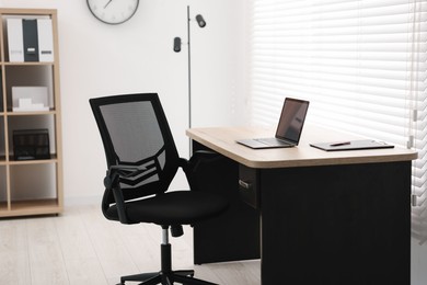 Photo of Black chair, laptop and desk in office