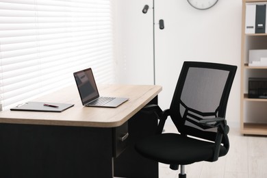 Photo of Black chair, laptop and desk in office