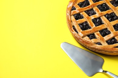 Photo of Tasty homemade pie with blueberries and server on yellow table, closeup. Space for text