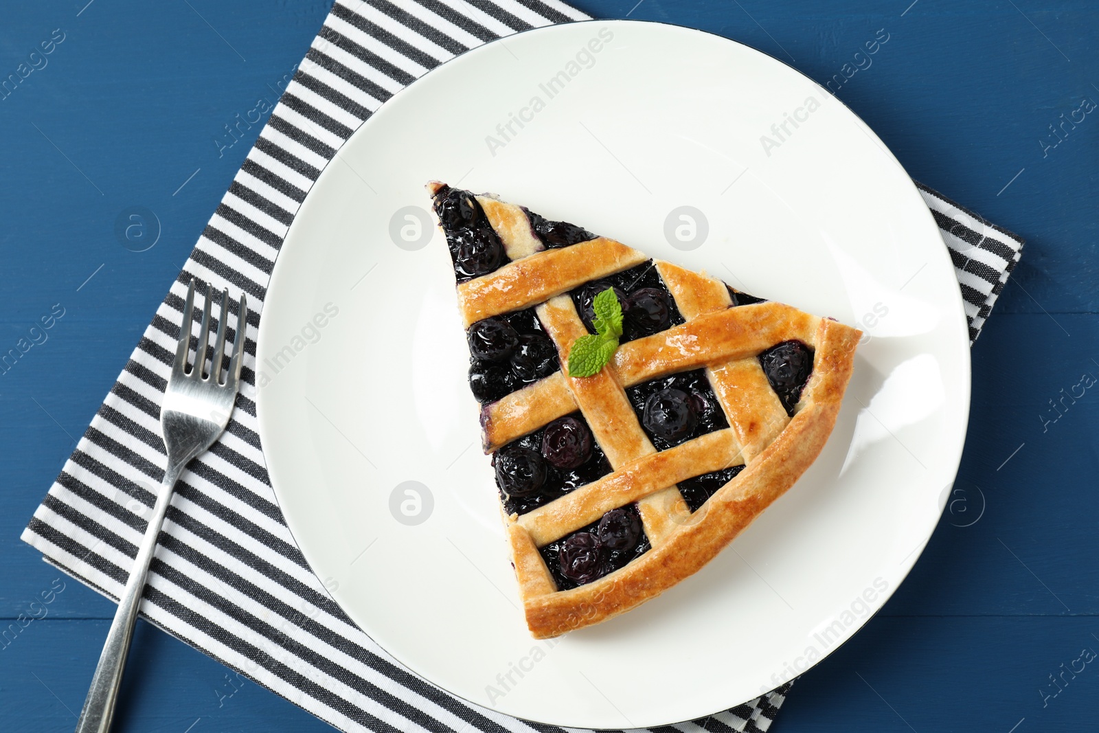 Photo of Piece of tasty homemade pie with blueberries served on blue wooden table, flat lay