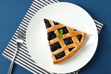 Photo of Piece of tasty homemade pie with blueberries served on blue wooden table, flat lay