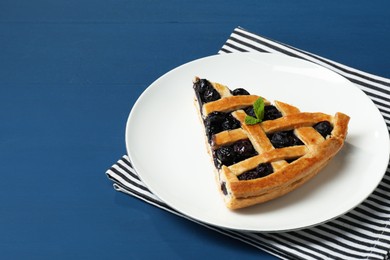 Photo of Piece of tasty homemade pie with blueberries on blue wooden table