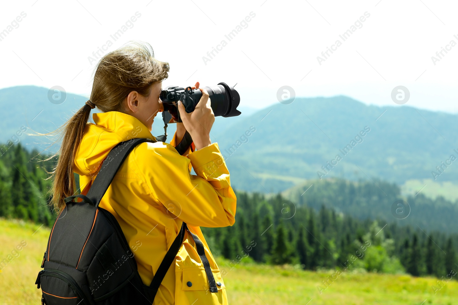 Photo of Photographer with backpack and camera taking picture of beautiful mountains. Space for text