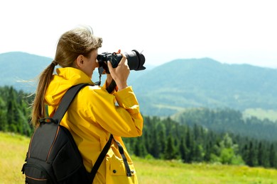 Photo of Photographer with backpack and camera taking picture of beautiful mountains. Space for text