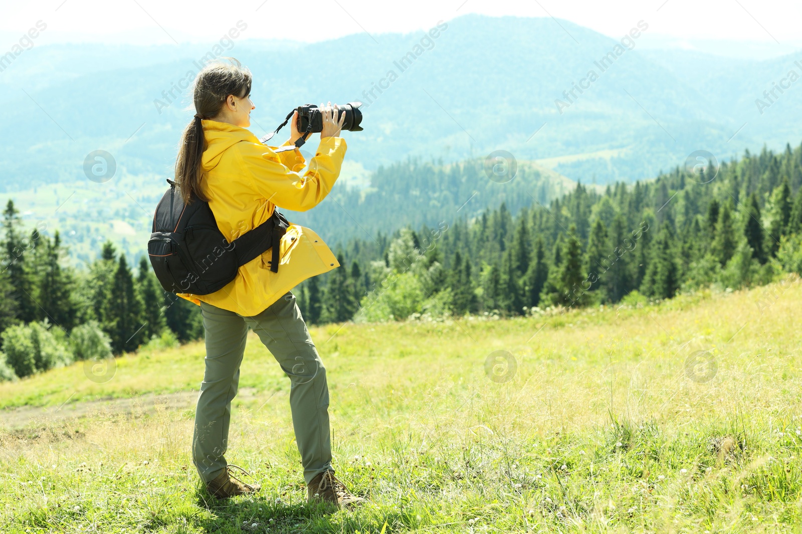 Photo of Photographer with backpack and camera taking picture of beautiful mountains. Space for text