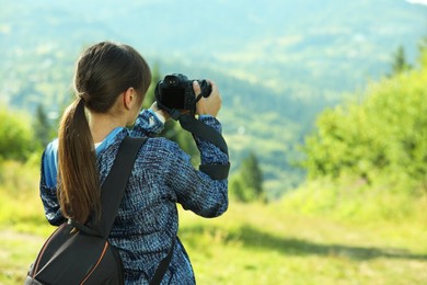 Photo of Photographer with backpack and camera taking picture of beautiful mountains, back view. Space for text