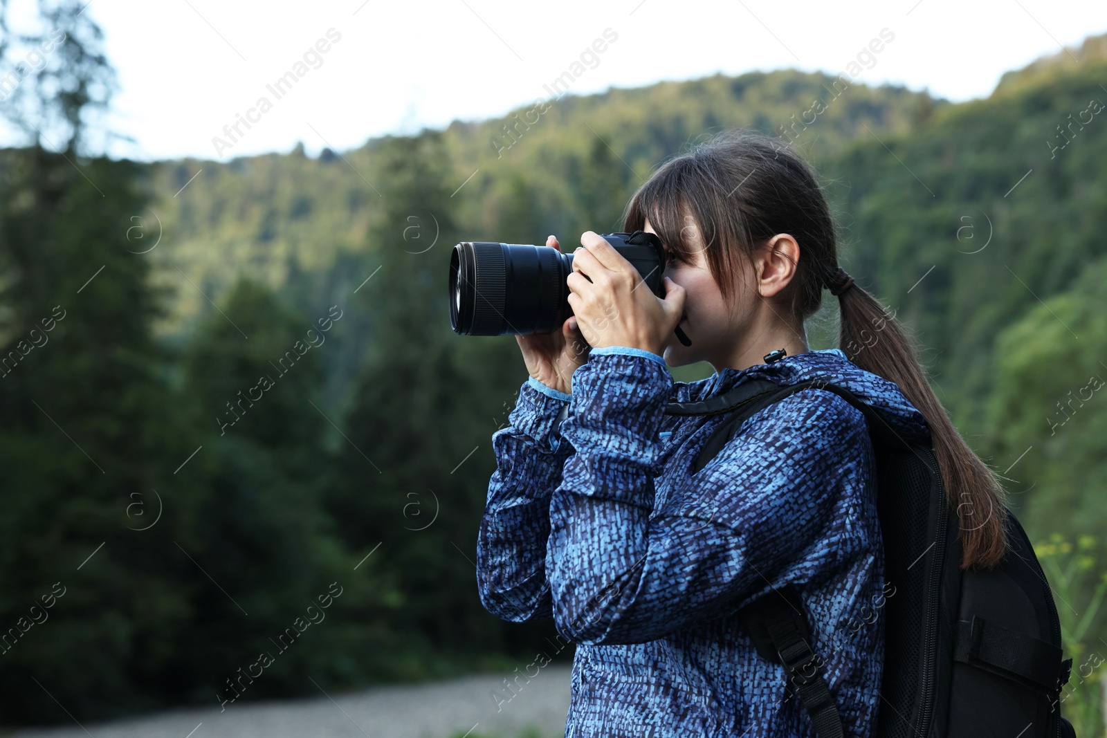 Photo of Photographer with backpack and camera taking picture of beautiful mountains