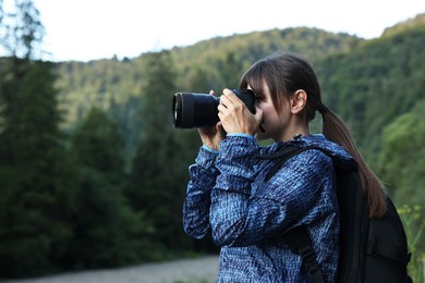 Photo of Photographer with backpack and camera taking picture of beautiful mountains