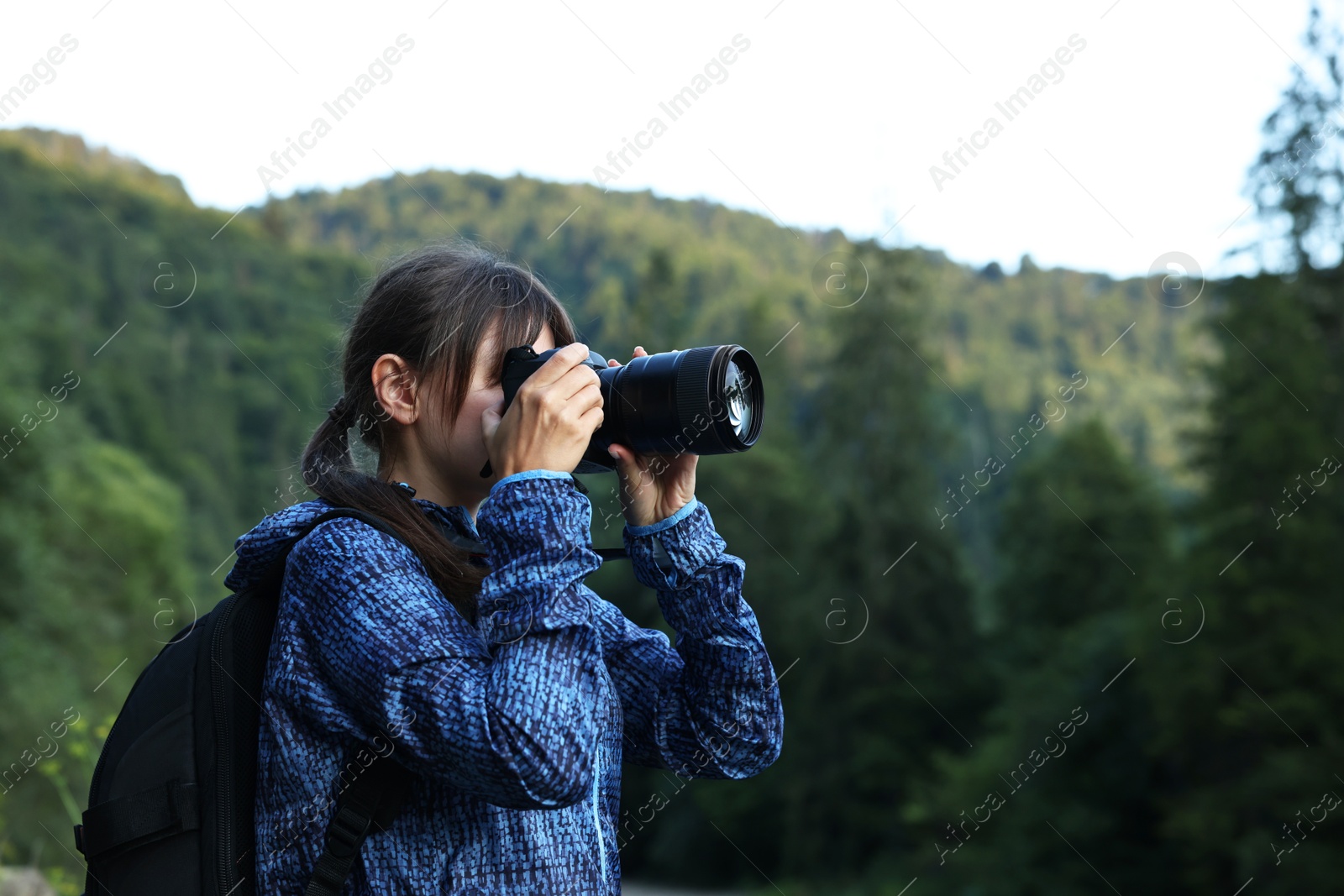 Photo of Photographer with backpack and camera taking picture of beautiful mountains