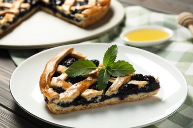 Photo of Piece of tasty homemade pie with blueberries and mint on table, closeup