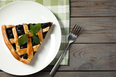 Photo of Piece of tasty homemade pie with blueberries served on wooden table, flat lay. Space for text