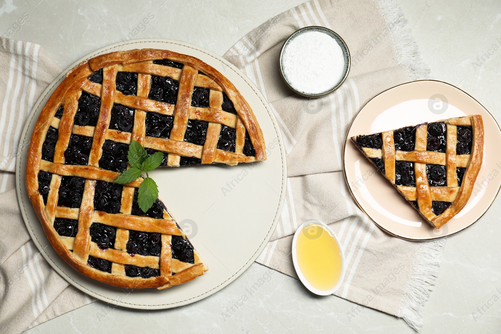 Photo of Tasty homemade pie with blueberries, honey and powdered sugar on gray textured table, flat lay