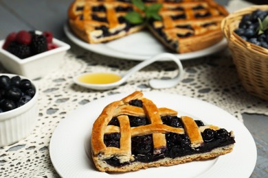 Photo of Piece of tasty homemade pie with blueberries on gray table, closeup