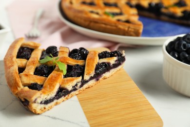 Photo of Piece of tasty homemade pie with blueberries on white table, closeup