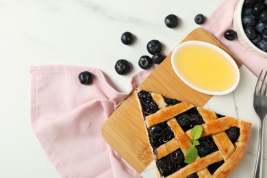 Photo of Tasty homemade pie with blueberries, honey and fork on white table, flat lay