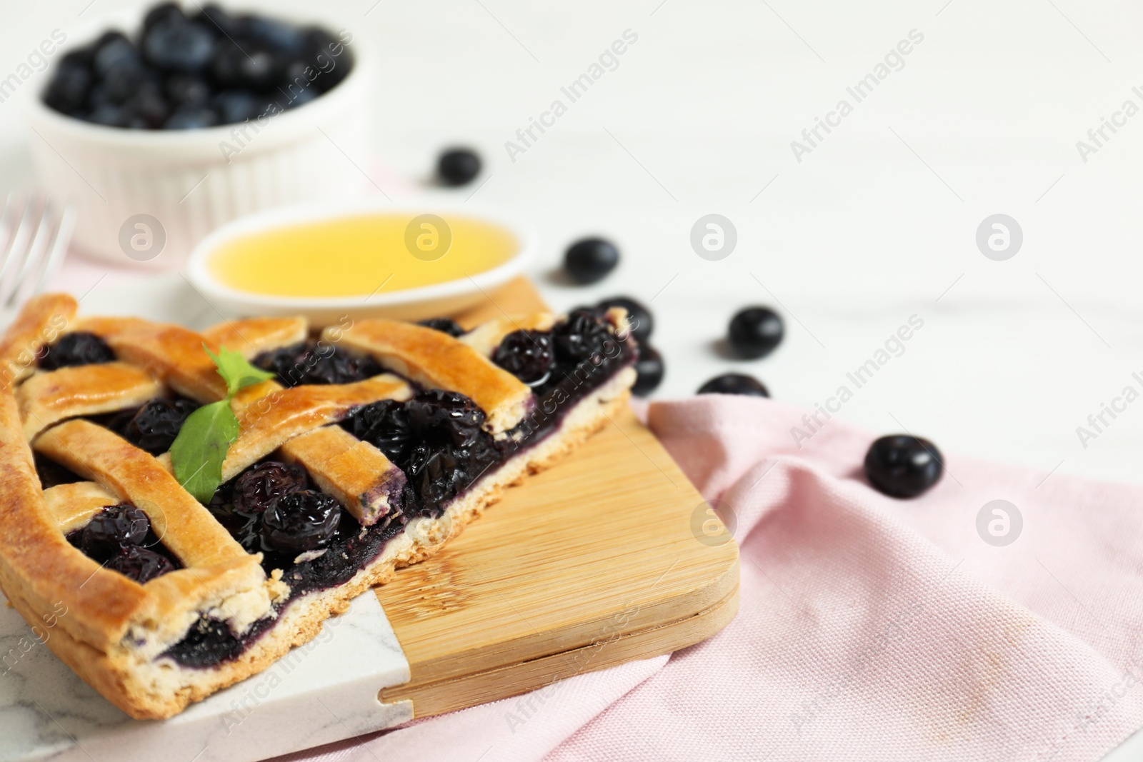 Photo of Piece of tasty homemade pie with blueberries on white table, closeup