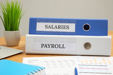 Photo of Payroll. Folders, charts and notebook on wooden table, closeup