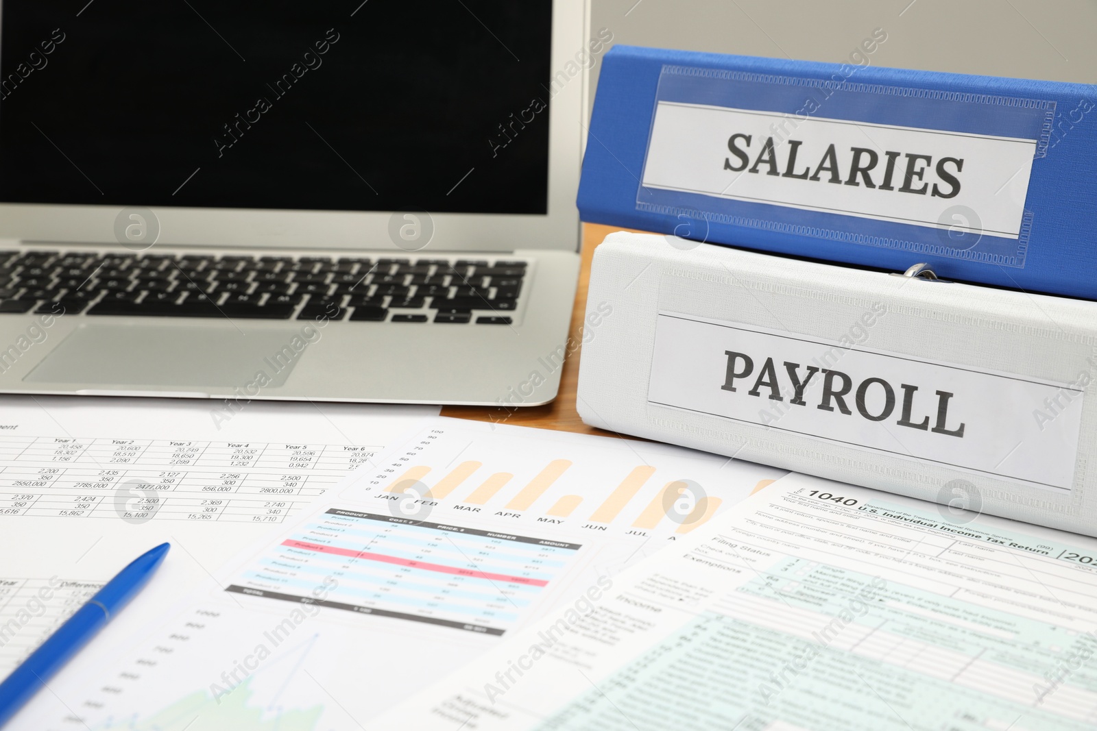 Photo of Payroll. Folders, charts and laptop on table, closeup