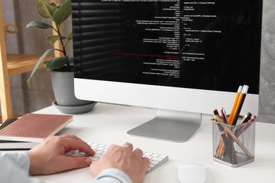 Photo of Programmer working with computer at white desk in office, closeup