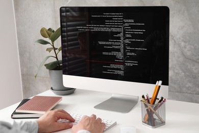 Photo of Programmer working with computer at white desk in office, closeup