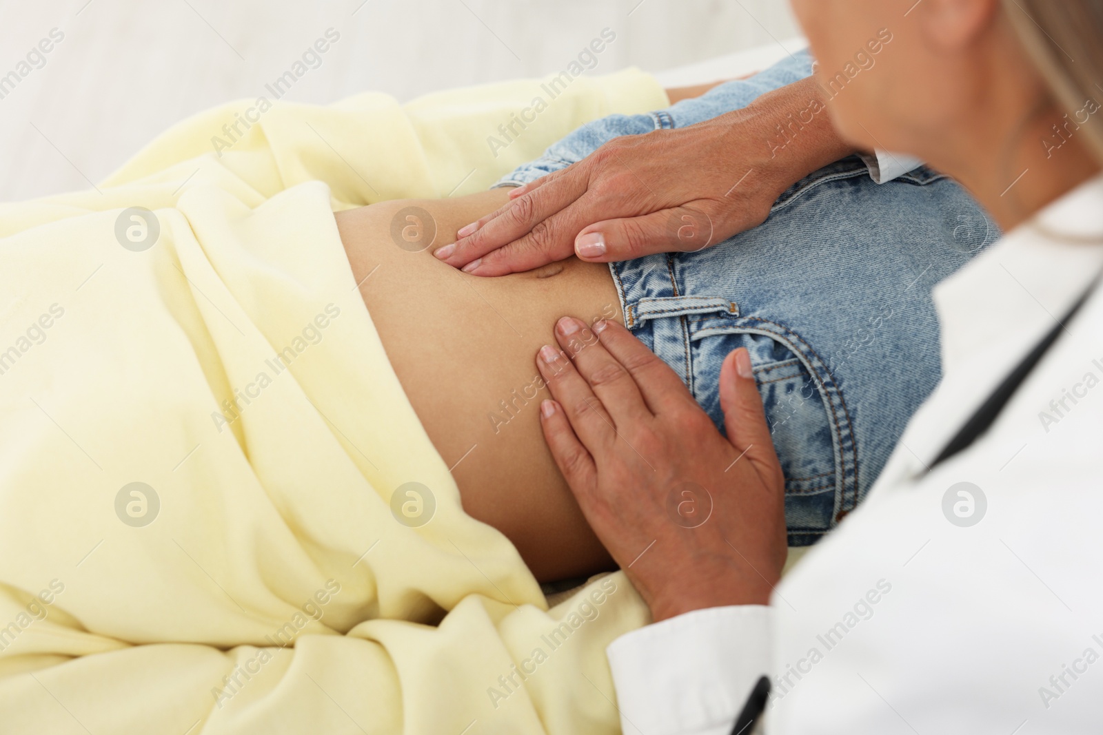 Photo of Doctor examining woman with stomach pain in clinic, closeup