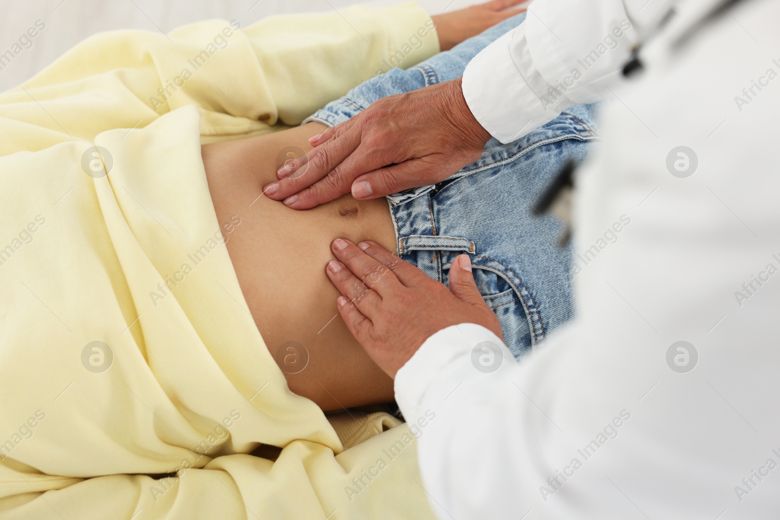 Photo of Doctor examining woman with stomach pain in clinic, closeup