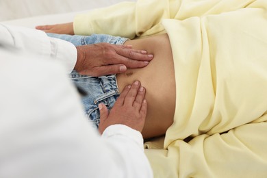 Photo of Doctor examining woman with stomach pain in clinic, closeup