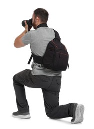 Photographer with backpack and camera taking picture on white background, back view