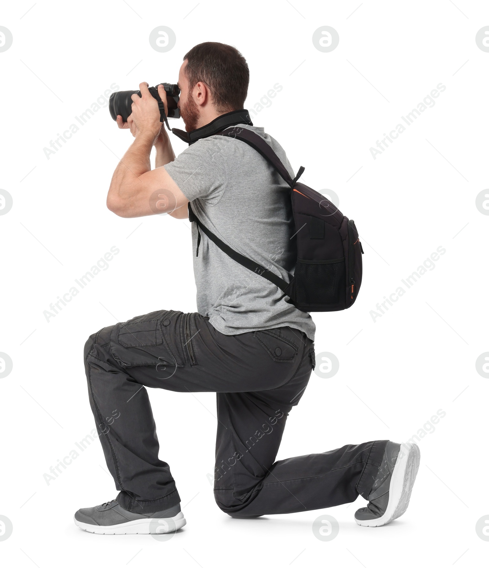 Photo of Photographer with backpack and camera taking picture on white background, back view