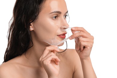 Photo of Beautiful woman peeling off face mask on white background