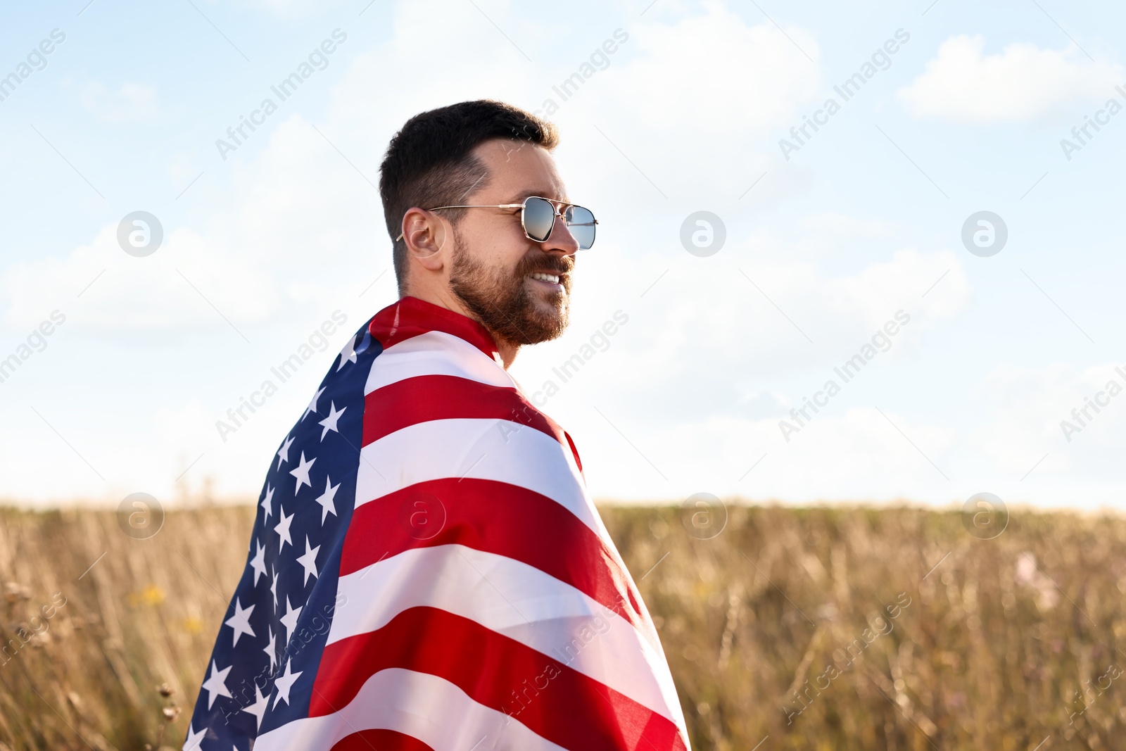 Photo of Happy man with flag of USA outdoors. Space for text